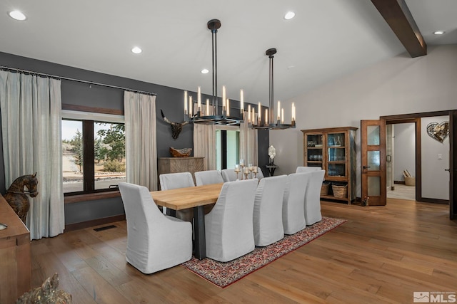 dining space featuring hardwood / wood-style flooring, vaulted ceiling with beams, and an inviting chandelier