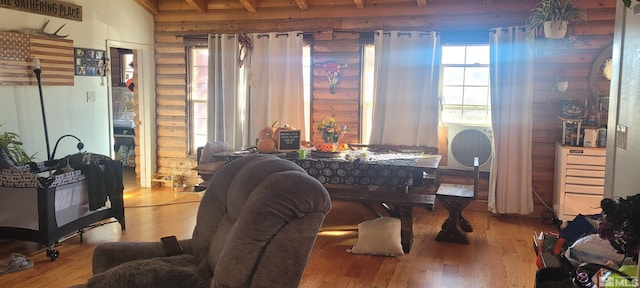 dining space with light hardwood / wood-style flooring, beam ceiling, and rustic walls