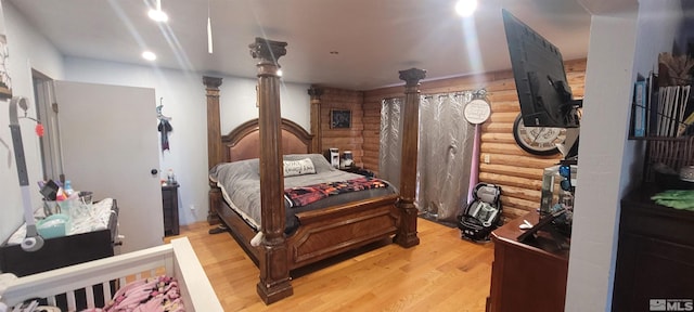 bedroom with log walls and light wood-type flooring