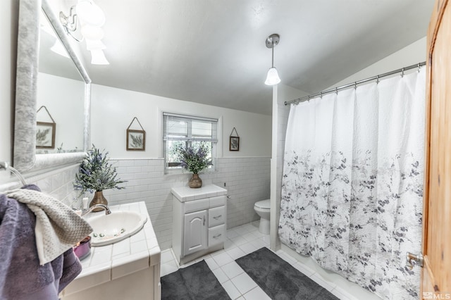 bathroom featuring vanity, toilet, tile patterned flooring, tile walls, and vaulted ceiling