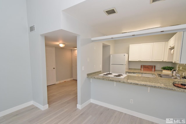 kitchen with light stone countertops, white cabinets, white appliances, sink, and kitchen peninsula