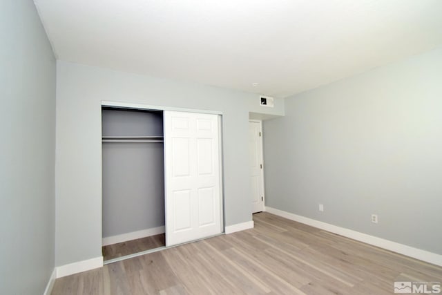 unfurnished bedroom with light wood-type flooring and a closet