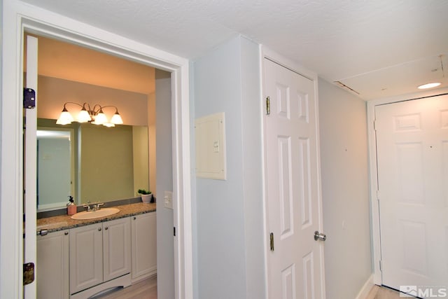 hallway featuring light hardwood / wood-style flooring, sink, and a textured ceiling