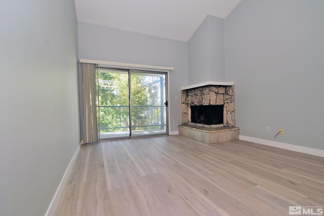 unfurnished living room with lofted ceiling, light hardwood / wood-style floors, and a fireplace