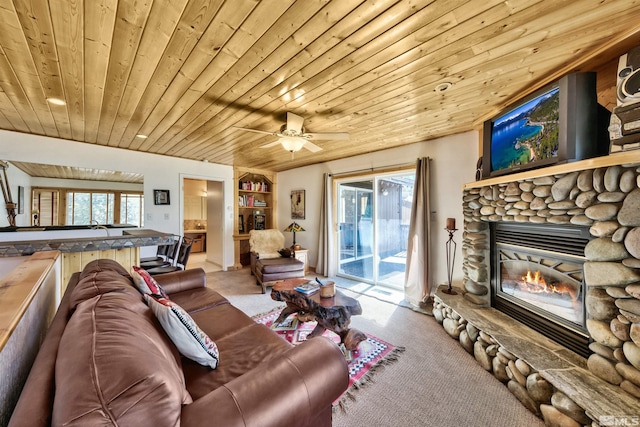 living room with plenty of natural light, wood ceiling, and a stone fireplace