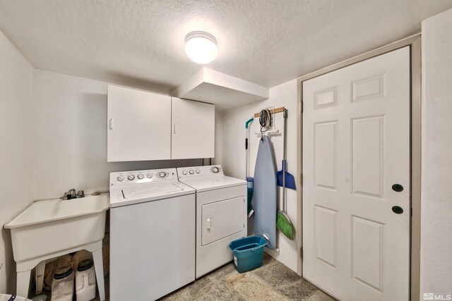 washroom with cabinets, washer and clothes dryer, sink, and a textured ceiling