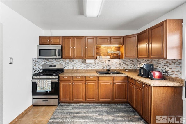 kitchen featuring appliances with stainless steel finishes, dark tile patterned floors, sink, and backsplash