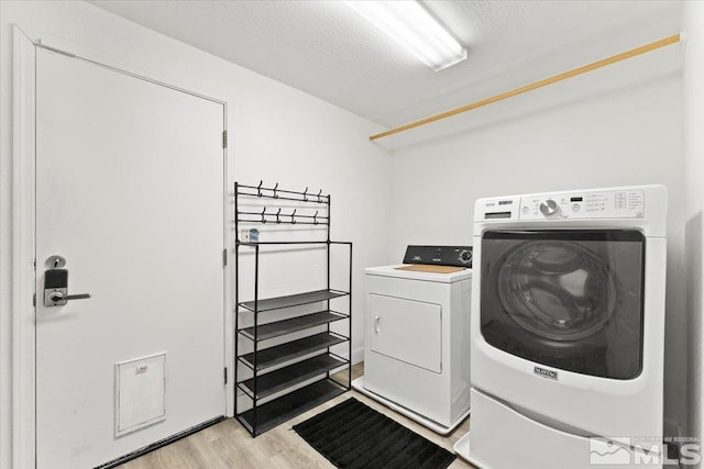 laundry area with separate washer and dryer and light wood-type flooring