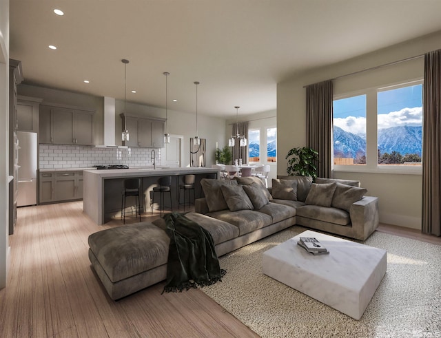 living room with a chandelier, light wood-type flooring, sink, and a mountain view