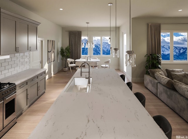 kitchen with gray cabinetry, light stone countertops, pendant lighting, and decorative backsplash