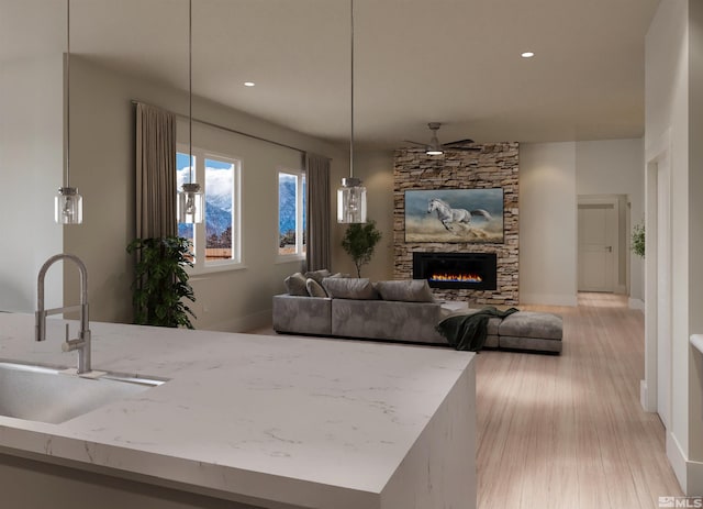 living room with a fireplace, ceiling fan, sink, and light hardwood / wood-style flooring