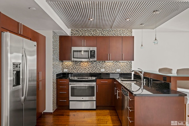 kitchen featuring hardwood / wood-style floors, hanging light fixtures, sink, appliances with stainless steel finishes, and kitchen peninsula