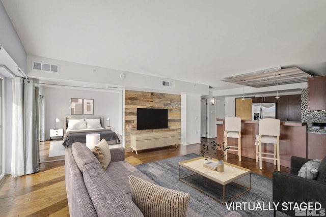 living room featuring an accent wall, wood finished floors, and visible vents