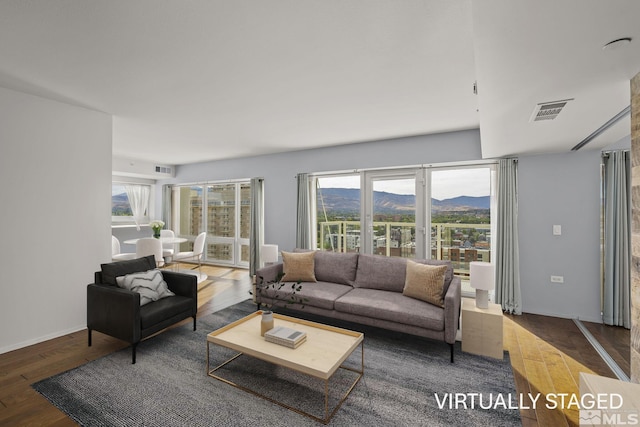 living area with a wealth of natural light, visible vents, a mountain view, and wood finished floors