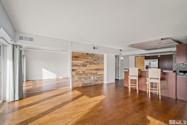 kitchen featuring hardwood / wood-style floors, a breakfast bar, visible vents, and stainless steel fridge with ice dispenser