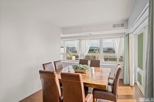 dining area with hardwood / wood-style flooring, a mountain view, and a wealth of natural light