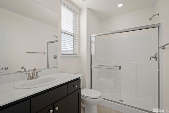 bathroom featuring tile patterned flooring, toilet, a shower with door, and vanity