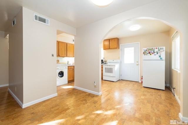 kitchen featuring white appliances, light wood-type flooring, and washer / dryer