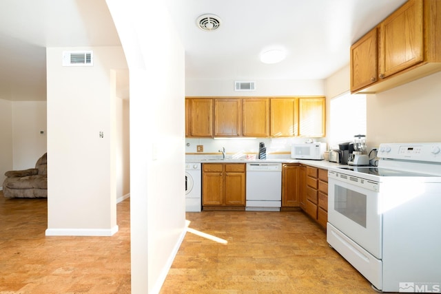 kitchen with sink, white appliances, and washer / dryer