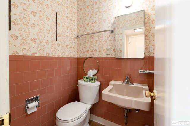 bathroom featuring sink, tile walls, and toilet