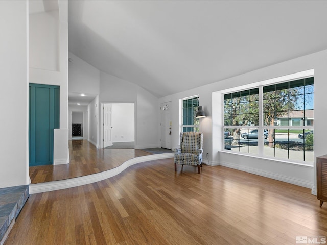 spare room with wood-type flooring and high vaulted ceiling