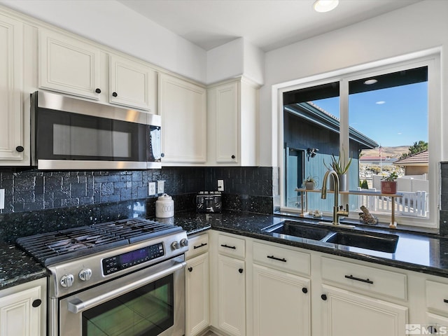 kitchen with dark stone countertops, appliances with stainless steel finishes, sink, and tasteful backsplash