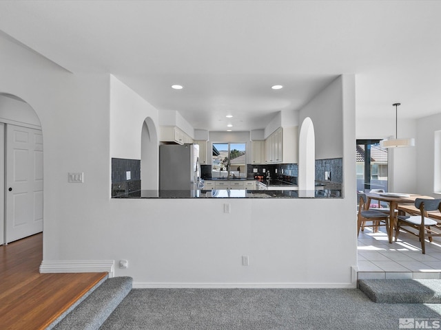 kitchen featuring kitchen peninsula, a wealth of natural light, stainless steel refrigerator, and decorative backsplash