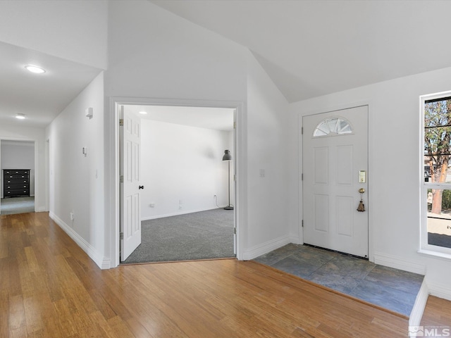 entrance foyer featuring lofted ceiling, wood-type flooring, and a healthy amount of sunlight