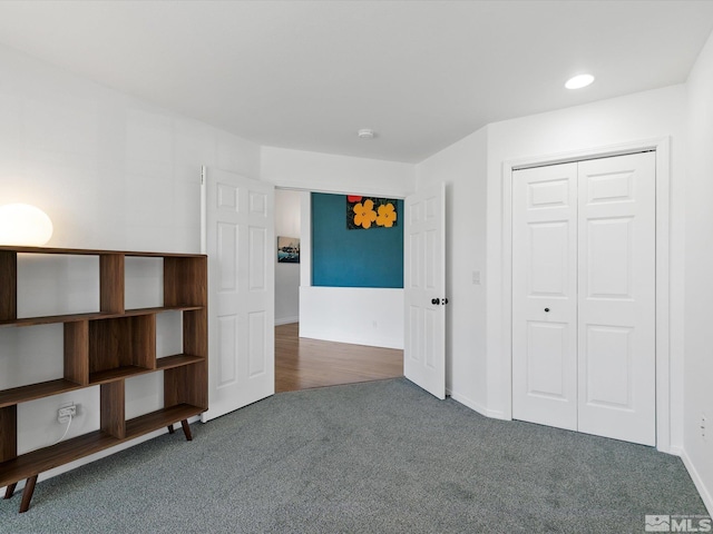 unfurnished bedroom with a closet and dark colored carpet