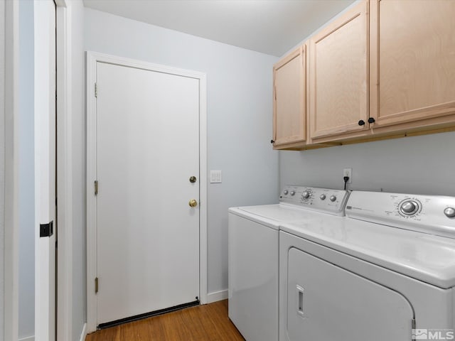 clothes washing area with light wood-type flooring, washing machine and clothes dryer, and cabinets