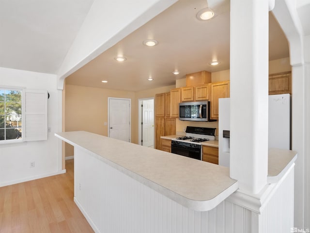 kitchen featuring light hardwood / wood-style flooring, a center island, vaulted ceiling, light brown cabinetry, and white appliances