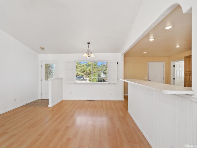 unfurnished living room featuring an inviting chandelier and light wood-type flooring