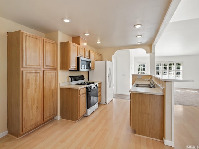 kitchen with white appliances, sink, light wood-type flooring, and light brown cabinets