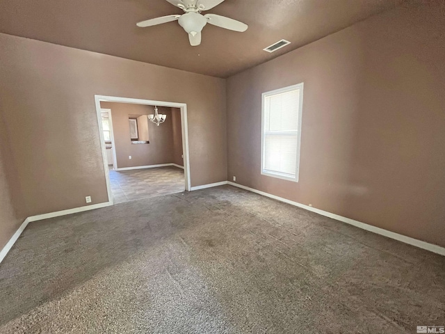 carpeted spare room featuring ceiling fan with notable chandelier