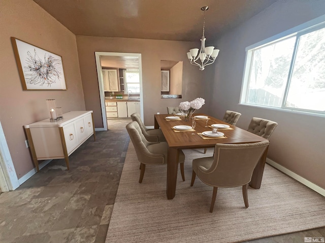 dining space featuring an inviting chandelier, dark wood-type flooring, sink, and a healthy amount of sunlight