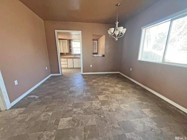 unfurnished dining area featuring sink, an inviting chandelier, and a healthy amount of sunlight