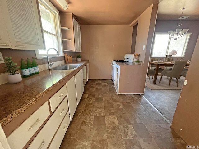 kitchen featuring an inviting chandelier, decorative light fixtures, sink, light stone counters, and white range oven