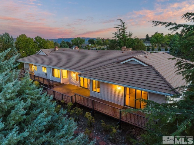 back house at dusk with a wooden deck