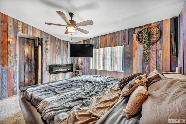 carpeted bedroom featuring wooden walls and ceiling fan