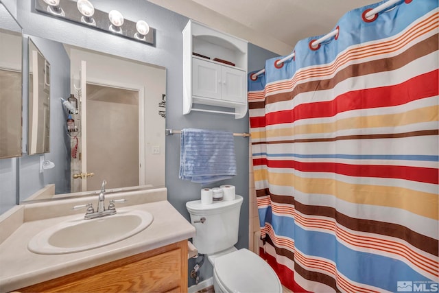 bathroom featuring toilet, walk in shower, and vanity