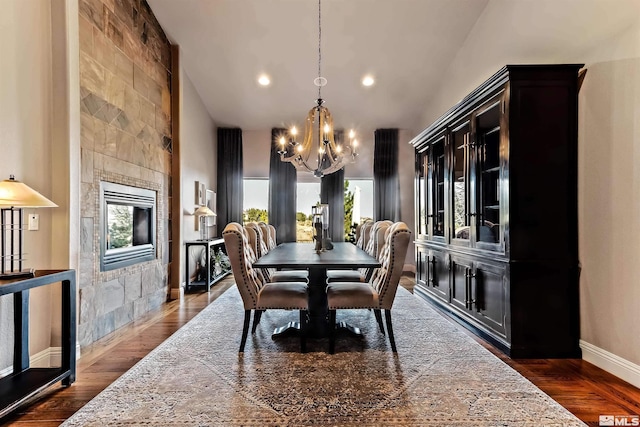 dining area featuring dark wood-type flooring, high vaulted ceiling, a notable chandelier, and plenty of natural light