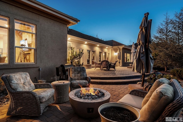 patio terrace at dusk featuring an outdoor fire pit