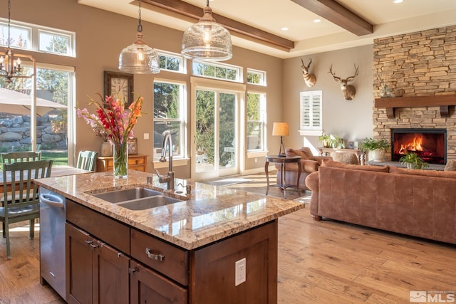 kitchen featuring sink, light hardwood / wood-style floors, decorative light fixtures, and light stone counters