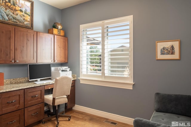 office with built in desk and light wood-type flooring