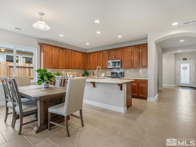 kitchen featuring appliances with stainless steel finishes, decorative light fixtures, plenty of natural light, and light tile patterned floors