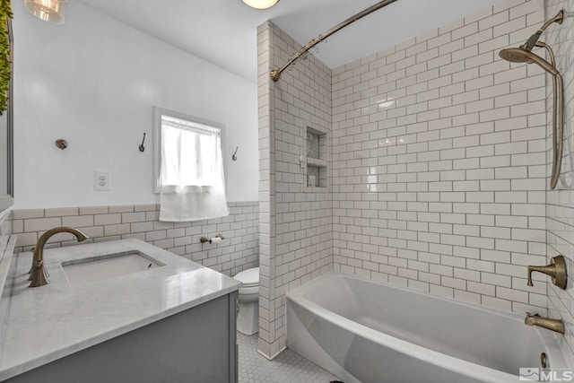 full bathroom with tile patterned floors, toilet, tiled shower / bath, tile walls, and vanity