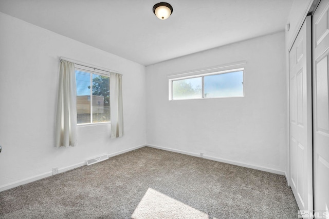 unfurnished bedroom featuring multiple windows, a closet, and carpet flooring