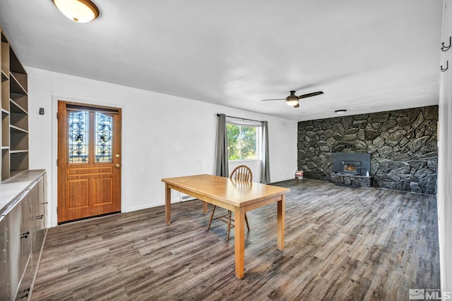 dining space with hardwood / wood-style floors, a wood stove, and ceiling fan