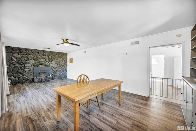 dining area featuring ceiling fan, built in features, a wood stove, and wood-type flooring