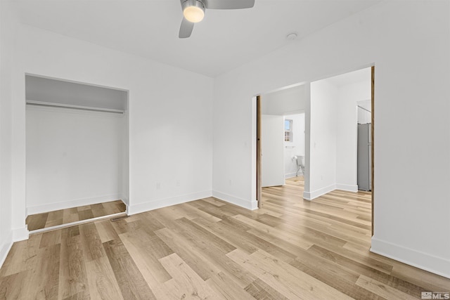 unfurnished bedroom with a closet, stainless steel refrigerator, light hardwood / wood-style floors, and ceiling fan